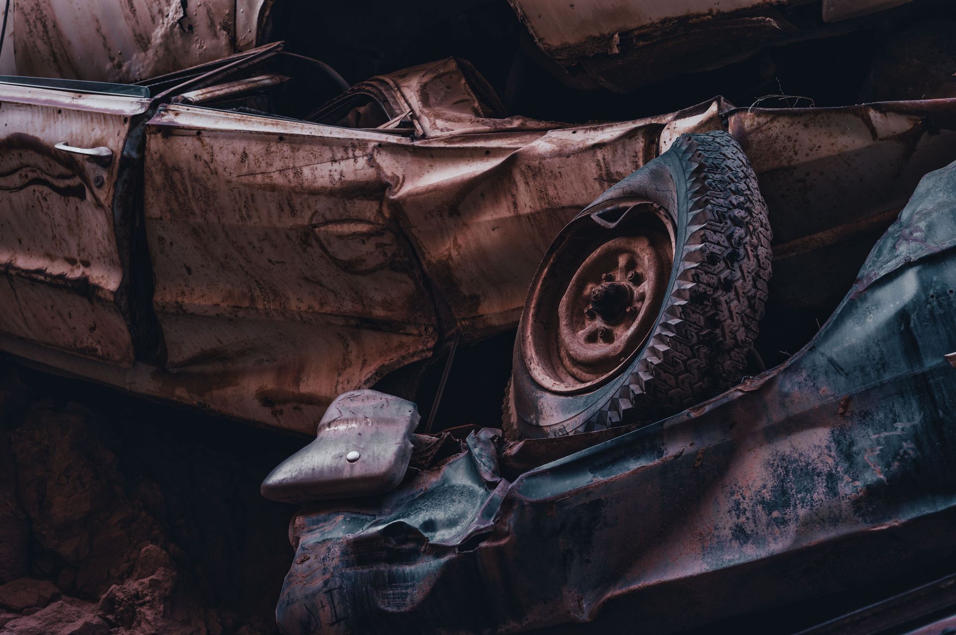 A dramatic view of stacked, rusty and abandoned cars in a junkyard, showcasing decay and abandonment.
