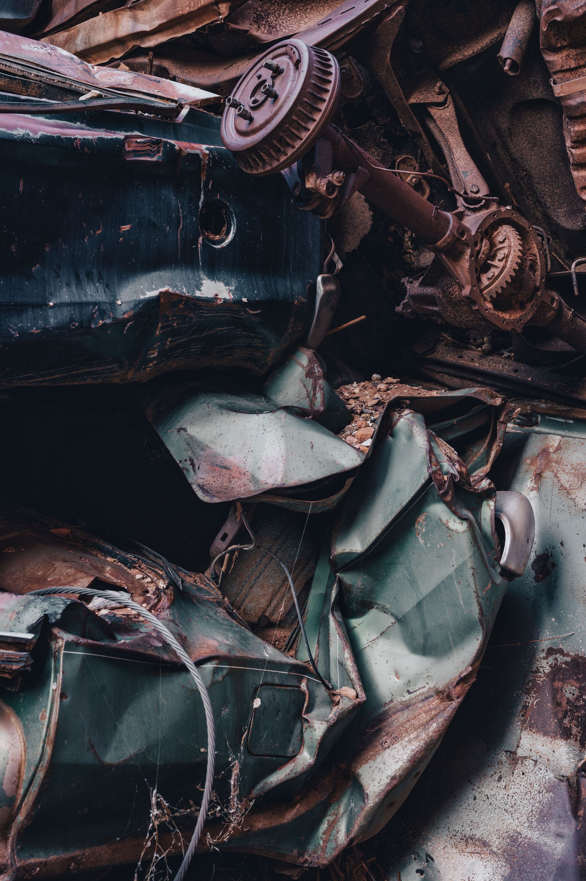 Detailed close-up of a pile of rusty, broken cars in a junkyard.