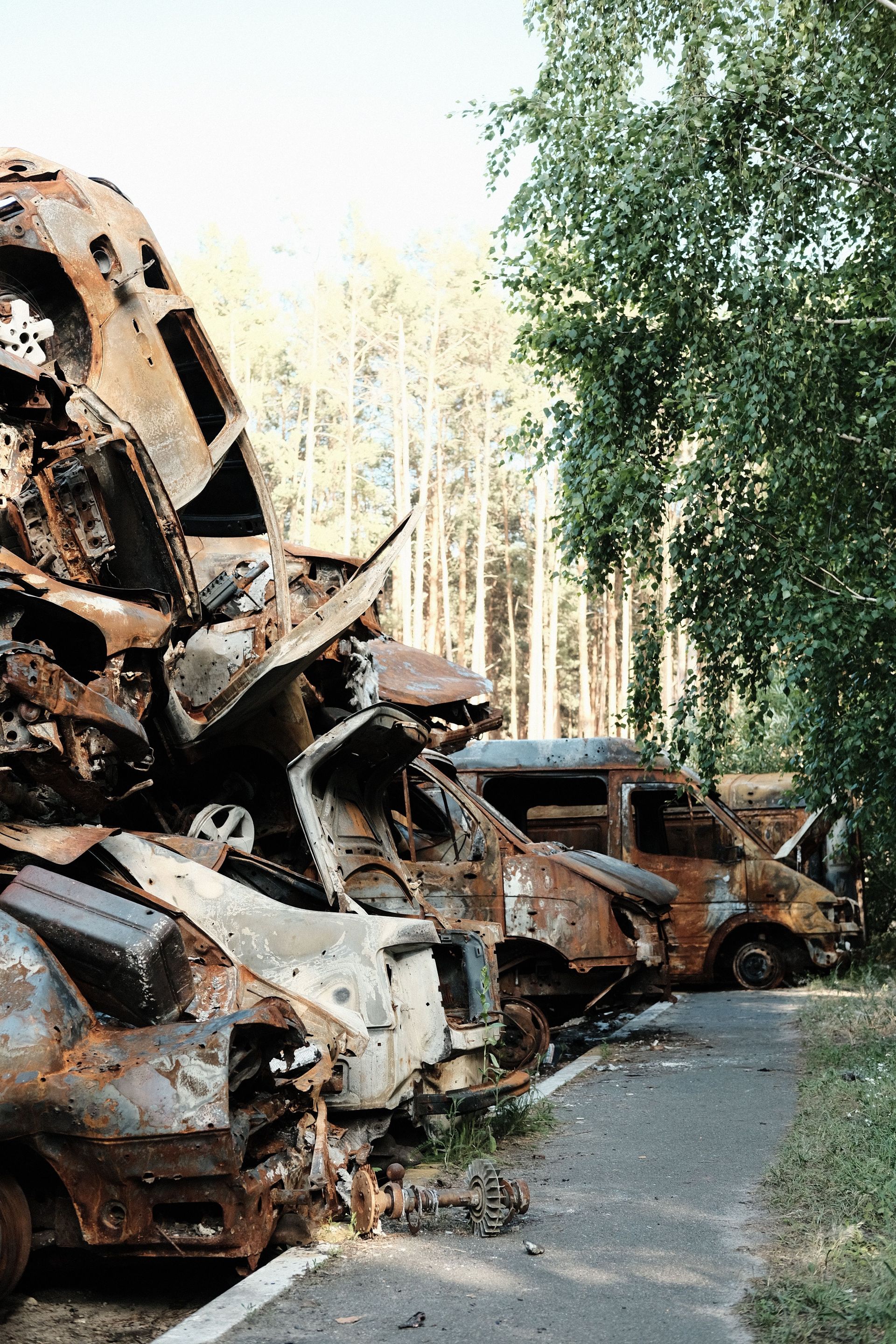A pile of corroded and wrecked cars stacked in an outdoor junkyard setting.